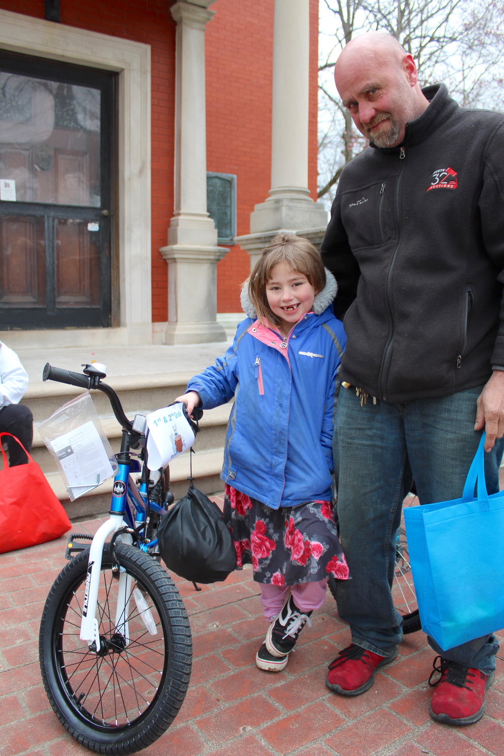 Mariah Walker, 7, accepts her prize Saturday alongside dad Steve Walker following the city’s annual Easter Egg Hunt on the grounds of the Lew Wallace Study. Bikes, sponsored by Nucor, were awarded to those lucky enough to find a golden egg in the scramble.